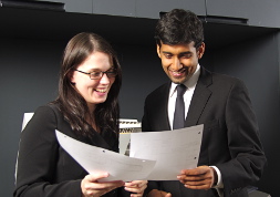 мужчина и женщина в деловой одежде радостно рассматривают документы