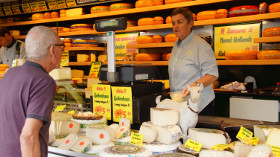 продавец сыров предлагает товар покупателю