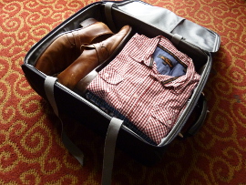 собранный в командировку чемодан со сменной рубашкой и ботинками